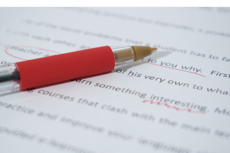 ein roter Stift liegt auf einem beschriebenen Papier. Der abgebildete Text wird korrigiert
